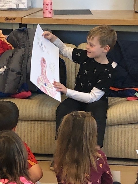 A student displaying his work at the 2023 Saturday Art Program.