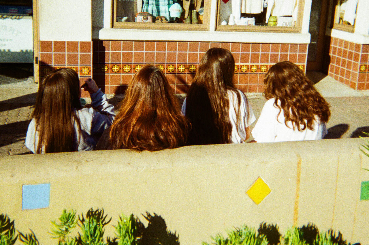 Color photograph of four girls sitting with their backs toward the camera, Untitled by Gabrielle Barrera, 2023; photo in Reed Gallery exhibit Long Exposure