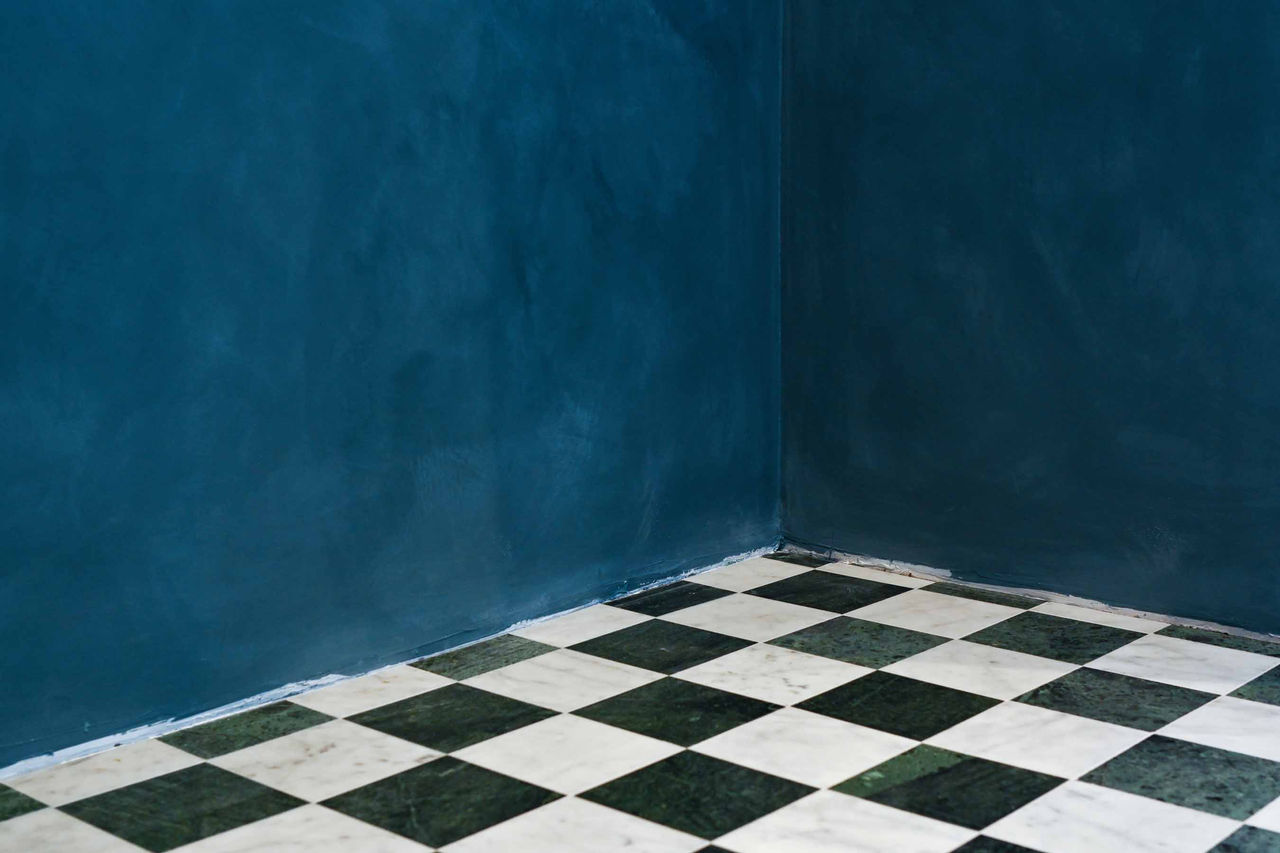 Color photograph of a black and white checkered floor and blue walls titled "Untitled" by Casey James Wilson, 2026; photograph in UC DAAP Galleries' Reed Gallery Exhibit Long Exposure