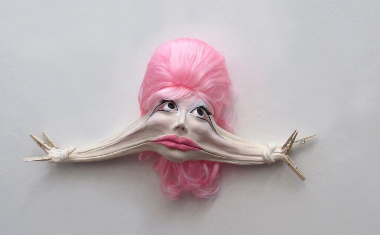 figure with pink hair and hands stretching from face